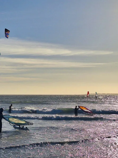 Windsurfers and kitesurfers on the beach at Blouberg in late afternoon light